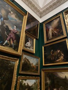 many paintings are hanging on the wall in a room with green walls and white ceiling