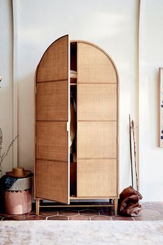 a wooden cabinet sitting on top of a tiled floor next to a potted plant