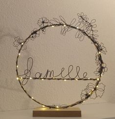 a wire wreath with the word danielle written in cursive writing on it and some lights