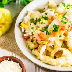 a bowl filled with pasta and vegetables next to some parsley on the side,