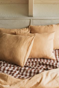 three pillows are on top of a bed with brown and white checkered linens