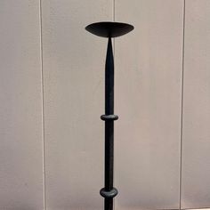 a tall black metal pole sitting next to a white wall