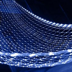 a blue and white photo with some lights on it's netted structure in the dark