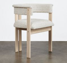 a wooden chair with a white upholstered seat and back rest on concrete floor