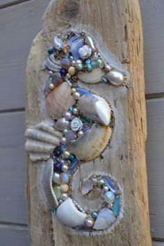 a wooden sign with shells and seashells painted on it's front side