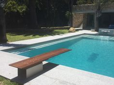 a wooden bench sitting next to a swimming pool