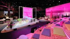 a stage set up for an event with pink lighting and purple carpeted flooring