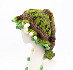 a crocheted hat with flowers on the brim and green tassels