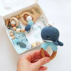 a hand holding a wooden ring with an elephant and whale toy in it's box