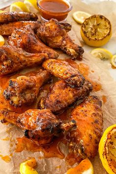 grilled chicken wings with lemons and ketchup on parchment paper next to sliced lemons