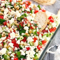 a salad with tomatoes, cucumbers, olives and feta cheese in a glass dish