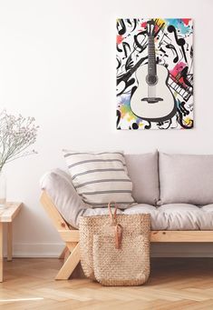 a living room with a couch, table and guitar painting on the wall above it