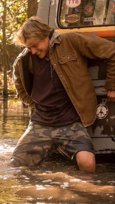 a man sitting in the water next to a truck