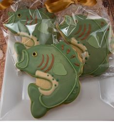 decorated cookies in the shape of fish sitting on a white plate with a gold bow