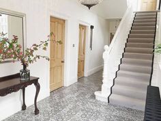 a foyer with stairs and flowers on the table