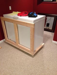 a white cabinet sitting on top of a carpeted floor next to a red wall