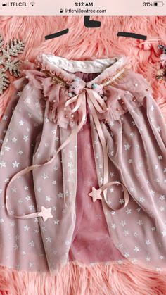 a pink skirt with stars on it sitting on top of a fur rug next to snowflakes