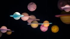 an array of planets hanging from strings in the dark