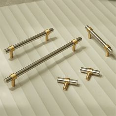 four different types of metal handles on a white surface with gold bars and knobs