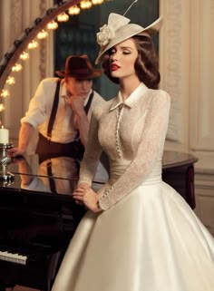 a woman in a white dress standing next to a piano