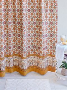 an orange and white shower curtain next to a bath tub with a towel on it