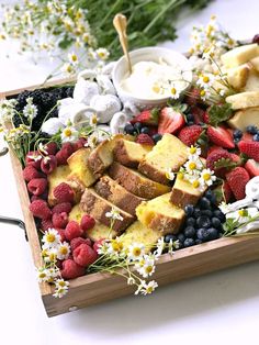 a wooden tray filled with different types of fruit and cake on top of a table