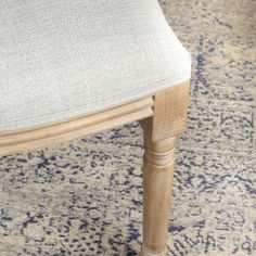 a close up of a wooden chair on a carpeted floor with blue and white designs