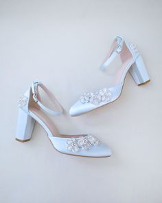 two pairs of white high heeled shoes with crystal embellishments on them