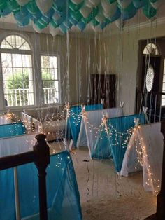 balloons and streamers are hanging from the ceiling in a room with blue tablecloths