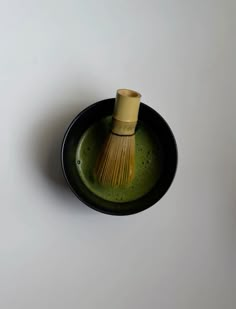 a black and green bowl with a yellow brush in the center on a white surface