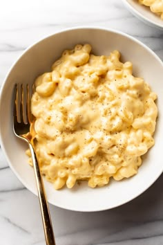 two bowls filled with macaroni and cheese on top of a marble countertop