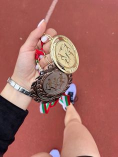 a woman holding two medals in her hand