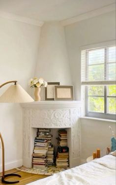 a bedroom with a white fireplace and lots of books