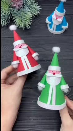 three paper hats with santa claus and snowmen on them, sitting next to pine branches