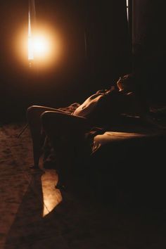 a person laying on a couch in the dark with a light shining down over their head