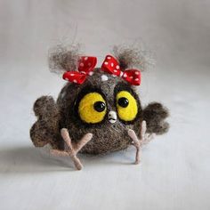 a close up of a stuffed animal on a white surface with a red bow in its hair