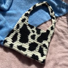 a black and white purse sitting on top of a bed next to a blue blanket