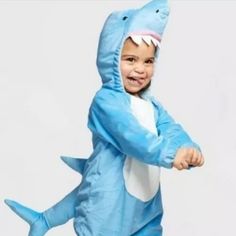 a little boy in a shark costume is smiling and holding his arms out to the side