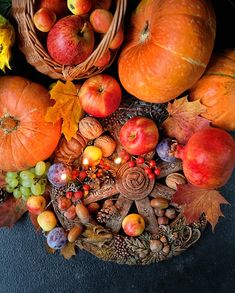 a basket filled with lots of different types of fruit next to pumpkins and apples