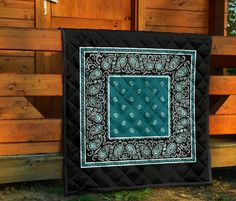 a black and green quilted wall hanging on a wooden fence