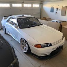 a white car parked in a garage next to two boxes and a box on the floor