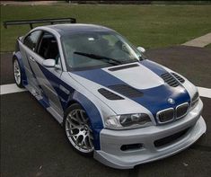 a blue and white car parked in a parking lot next to a grass covered field