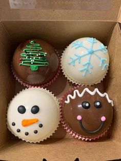 four decorated cupcakes in a cardboard box