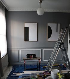 a ladder is in the middle of a room with gray walls and white paneling