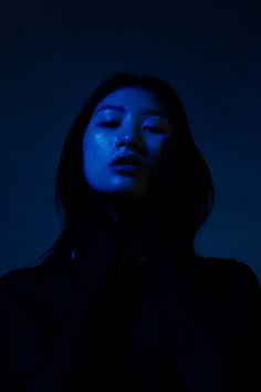 a woman with her eyes closed in the dark, she is wearing a black jacket