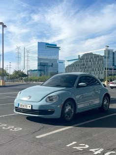 a blue car parked in a parking lot next to tall buildings