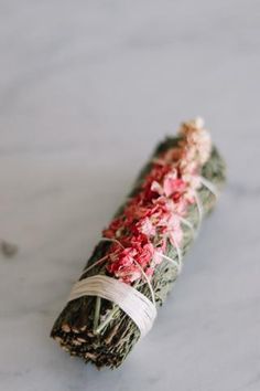 a bundle of dried flowers sitting on top of a white countertop next to a roll of twine