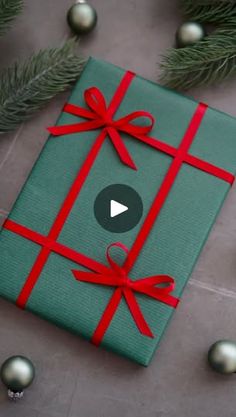 a green present wrapped in red ribbon and surrounded by christmas ornaments