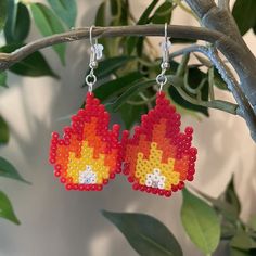 a pair of fire earrings hanging from a tree branch