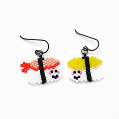 pair of earrings made out of legos with black string and white beads on them